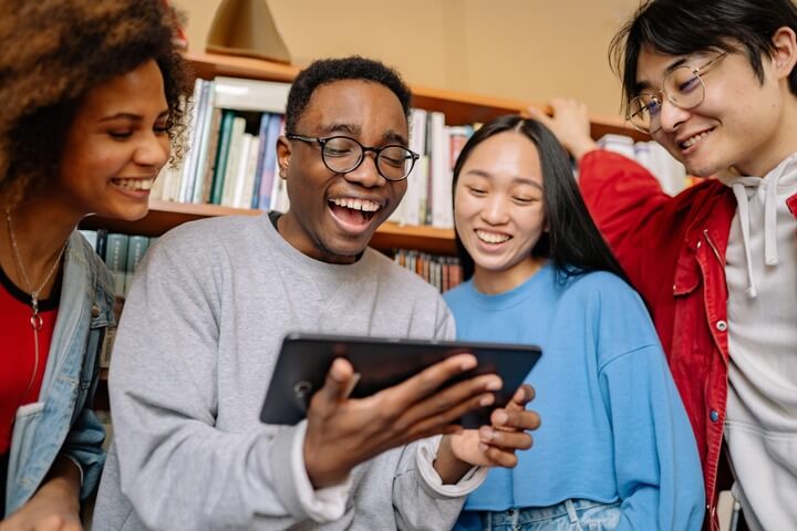 Students laughing around tablet